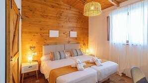 Een kamer met houten lambrisering, een bed, twee nachtkastjes en een hanglamp.