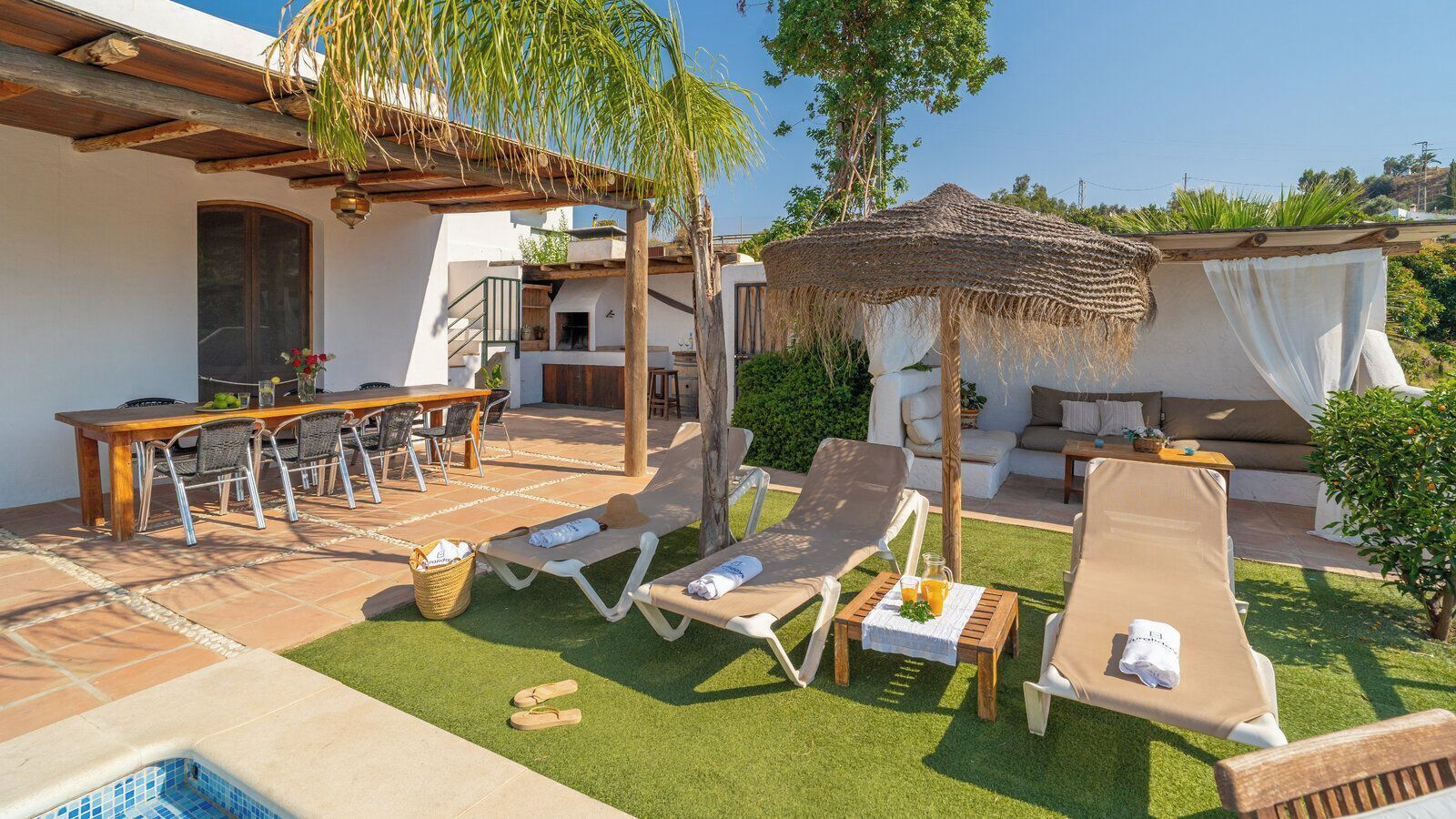 Une terrasse avec des chaises longues, une table à manger et une petite piscine.
