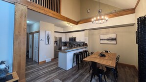 A spacious kitchen with a central island, wooden ceiling beams, and a chandelier.