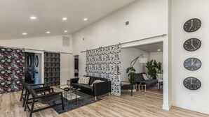 A spacious living area with a black sofa, a coffee table, and a patterned partition.