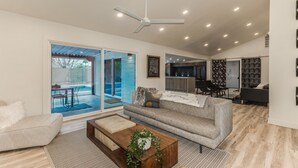 A modern living room with a sofa, coffee table, and a dining area with chairs.