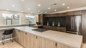 A modern kitchen with a large island, dark wood cabinets, and stainless steel appliances.