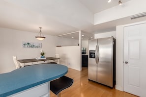 A modern kitchen with a blue countertop, stainless steel refrigerator, and a dining area with a white chair and table. - Tranquil Waterfront Scottsdale Townhome (Scottsdale)