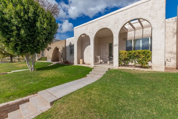 A building with a white stucco exterior, three arched doorways, and a well-maintained lawn. - Tranquil Waterfront Scottsdale Townhome (Scottsdale)