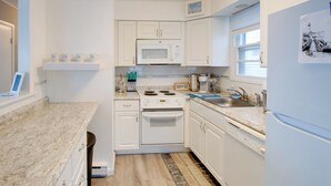 A modern kitchen with white cabinets, a microwave, a stove, and a refrigerator.