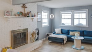 A living room with a fireplace, a blue sofa, a round coffee table, and a brick wall.