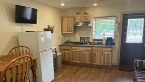 Una cocina compacta con armarios de madera, un refrigerador, un microondas y un lavamanos.