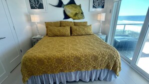 Une chambre à coucher avec un grand lit, deux lampes fixées au mur et des œuvres d’art encadrées.