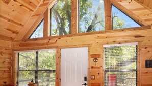 L'intérieur d'un chalet en bois, avec une table à manger, des chaises et une porte blanche.