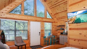 Una cabaña de madera con una cama, un escritorio, una silla y un televisor.
