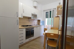 A kitchen with white cabinets, a gas stove, an oven, a sink, and a dining table with chairs.