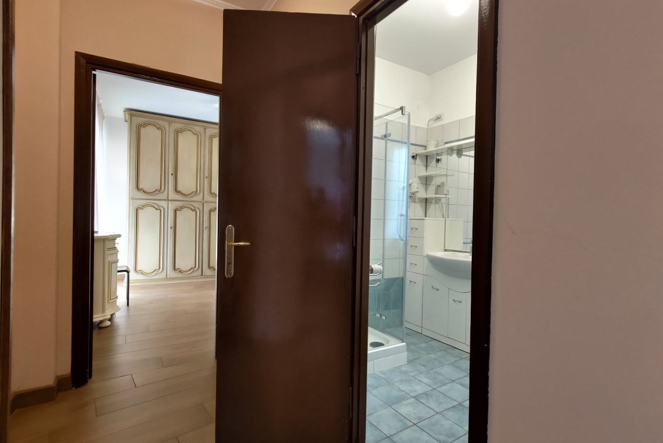 En gang der fører til et badeværelse med bruser, toilet og vask.
