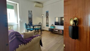 Een kamer met een bed, een eettafel met stoelen, een televisie en een deur met slot.