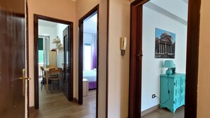 Een gang met een houten deur, een blauwgroene kast en een ingelijste foto aan de muur.