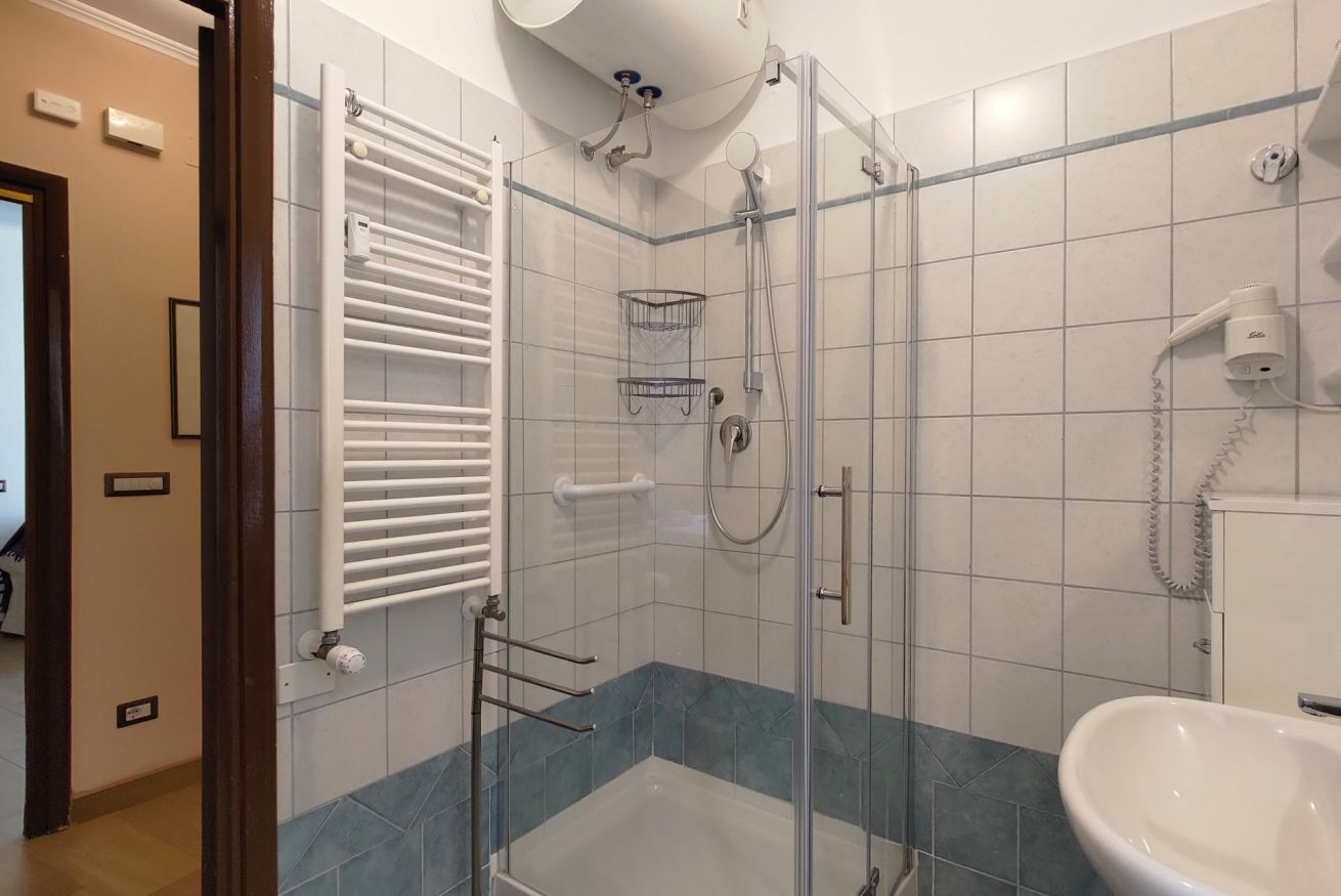 Une salle de bain avec une douche à parois de verre, un lavabo blanc et un porte-serviettes.