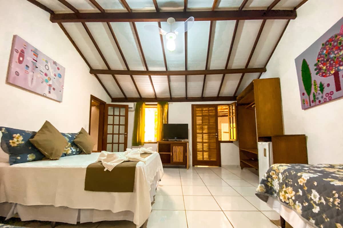 Una habitación con una cama, un escritorio, un televisor y una puerta.