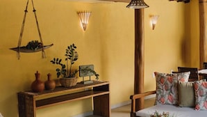 Une pièce chaleureuse et rustique, avec des meubles en bois, une plante suspendue et des lampes fixées au mur.