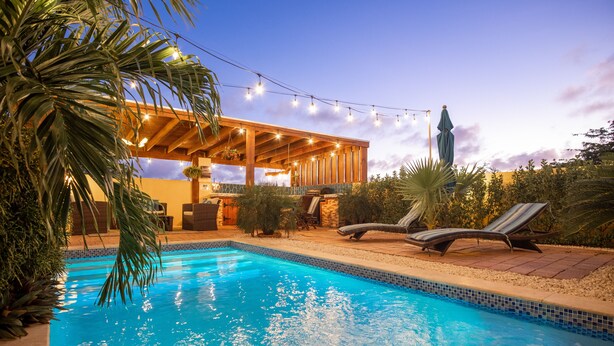 Une piscine avec des chaises longues et un espace patio couvert.