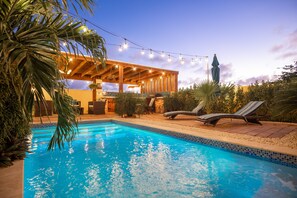 Ein Schwimmbecken mit Liegestühlen und einer überdachten Terrasse.
