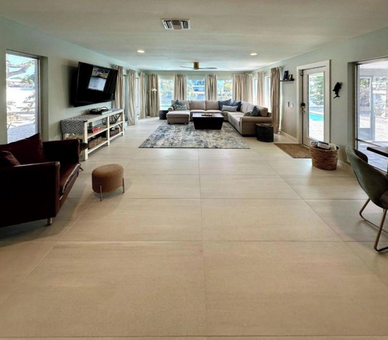 A spacious living room with a large sofa set, a coffee table, and a television mounted on the wall.