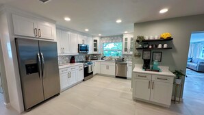 Una cocina moderna con armarios blancos, electrodomésticos de acero inoxidable y un ventanal con vistas.