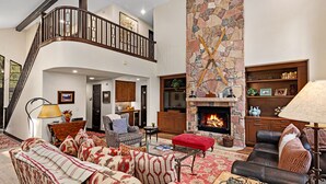 A spacious living room with a fireplace, a staircase, and a kitchen area. - Single family remodeled platinum level home with private hot tub!! (Beaver Creek)