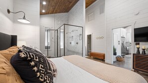 A modern bedroom with a large bed, a walk-in closet, and a glass shower enclosure. - Luxury Honeymoon/Small Family, Hot Tub, Firewood Included (Broken Bow)