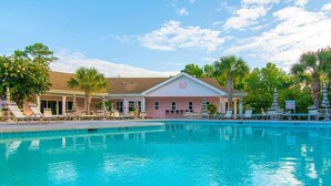 A swimming pool with lounge chairs and umbrellas, a building with a pink facade, and palm trees in the background. - 1st Floor, 2 BR, 2 Bath Sunset Beach 5 minutes to ocean @ Sea Trail Golf Resort! (Sunset Beach)