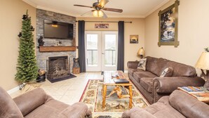 A living room with a fireplace, a television, a ceiling fan, and a couch. - Beautiful Upgraded Luxury Condo in Great Location with Mtn Views & Great Beds (Pigeon Forge)