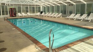 An indoor swimming pool with clear water, surrounded by white lounge chairs and a Coca-Cola vending machine. - Beautiful Upgraded Luxury Condo in Great Location with Mtn Views & Great Beds (Pigeon Forge)