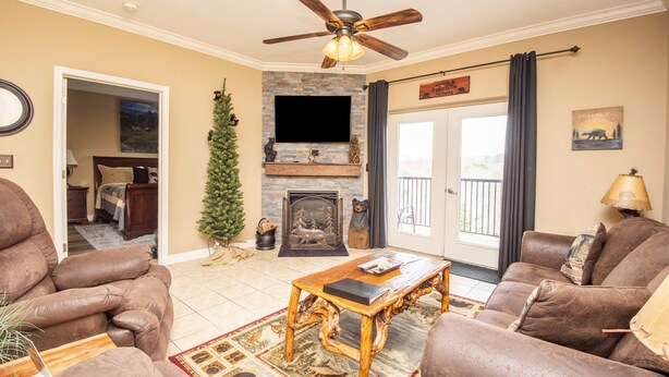 A living room with a fireplace, a ceiling fan, and a television. - Beautiful Upgraded Luxury Condo in Great Location with Mtn Views & Great Beds (Pigeon Forge)