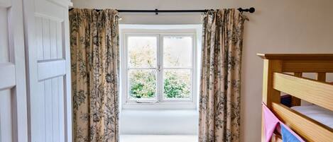 Ein Zimmer mit Fenster, Heizkörper, einem hölzernen Bett und Vorhängen.