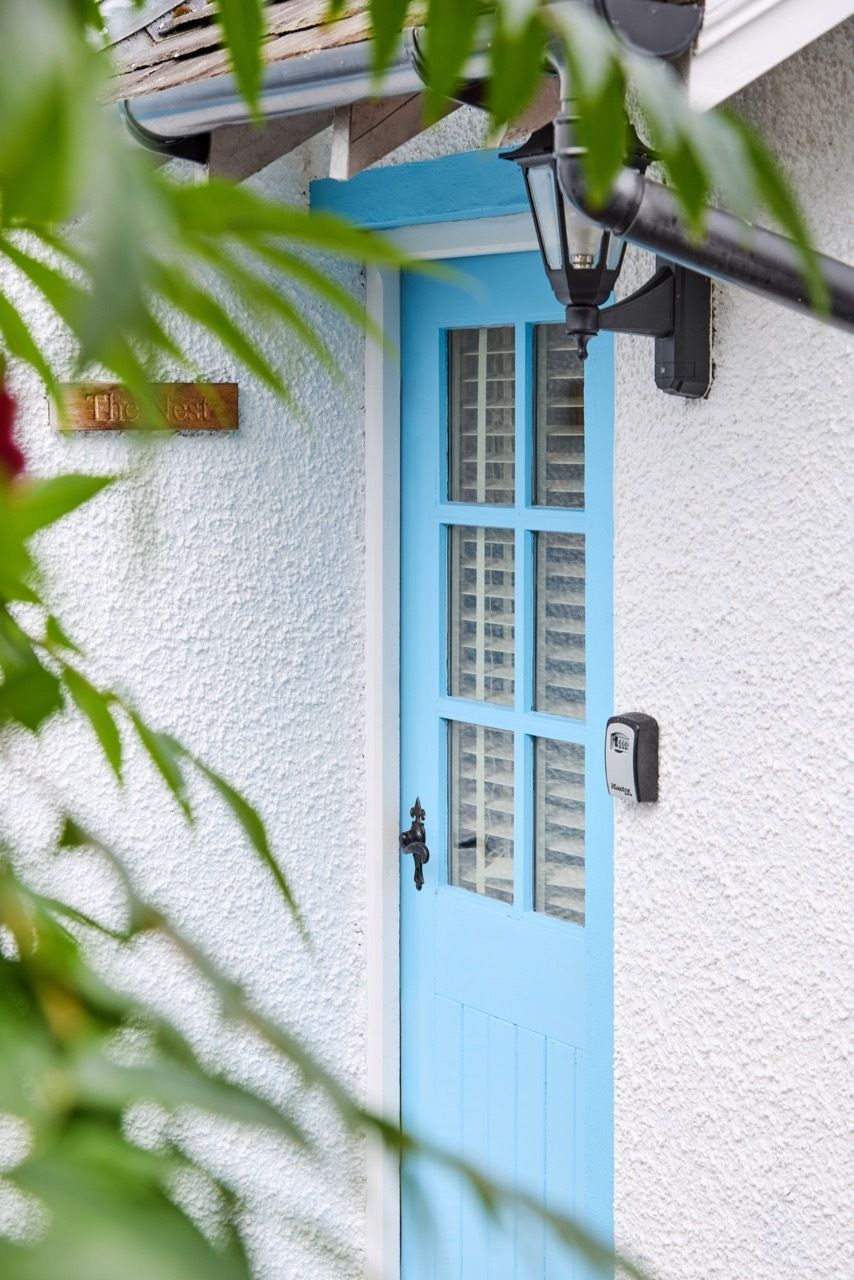 A blue door with a window, a mailbox, and a sign that reads 'The Nest.'