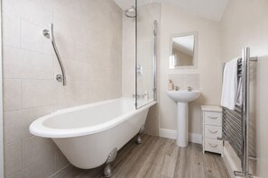 A modern bathroom with a freestanding bathtub, a pedestal sink, and a glass-enclosed shower. - Maggie Puddle Cottages (Grange-over-Sands)