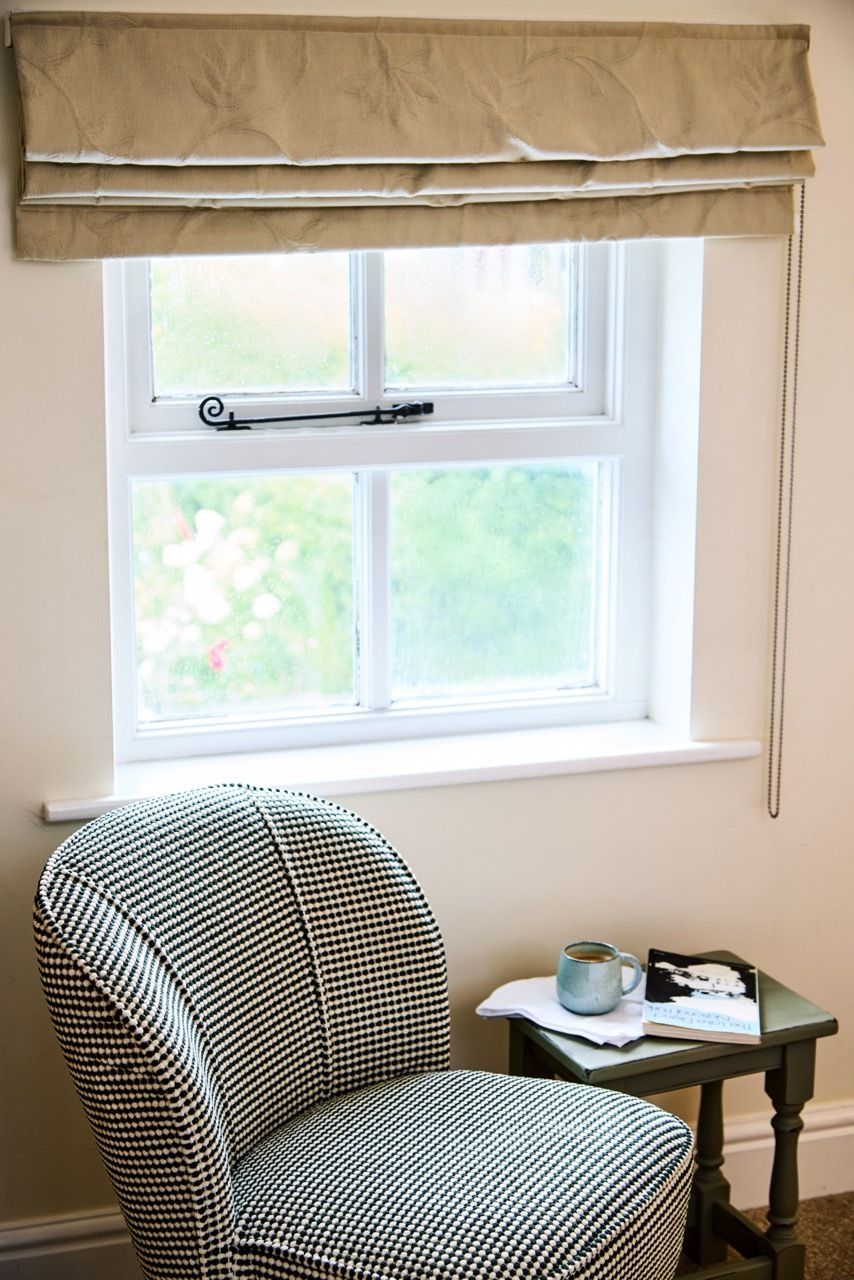 A room with a window, a chair, a small table, and a book.