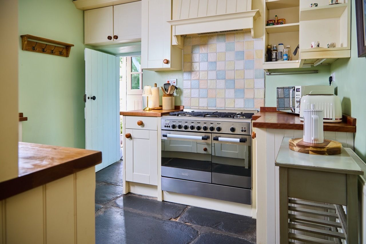 A kitchen with white cabinets, a stove, an oven, and a coffee maker.
