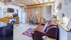 Ein kompakter Wohnbereich mit Küchenzeile, Essbereich und einer Sitzecke mit Sofa und Tisch.