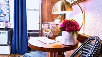 A wooden table with a lamp, a vase with flowers, a glass of wine, and a notebook.