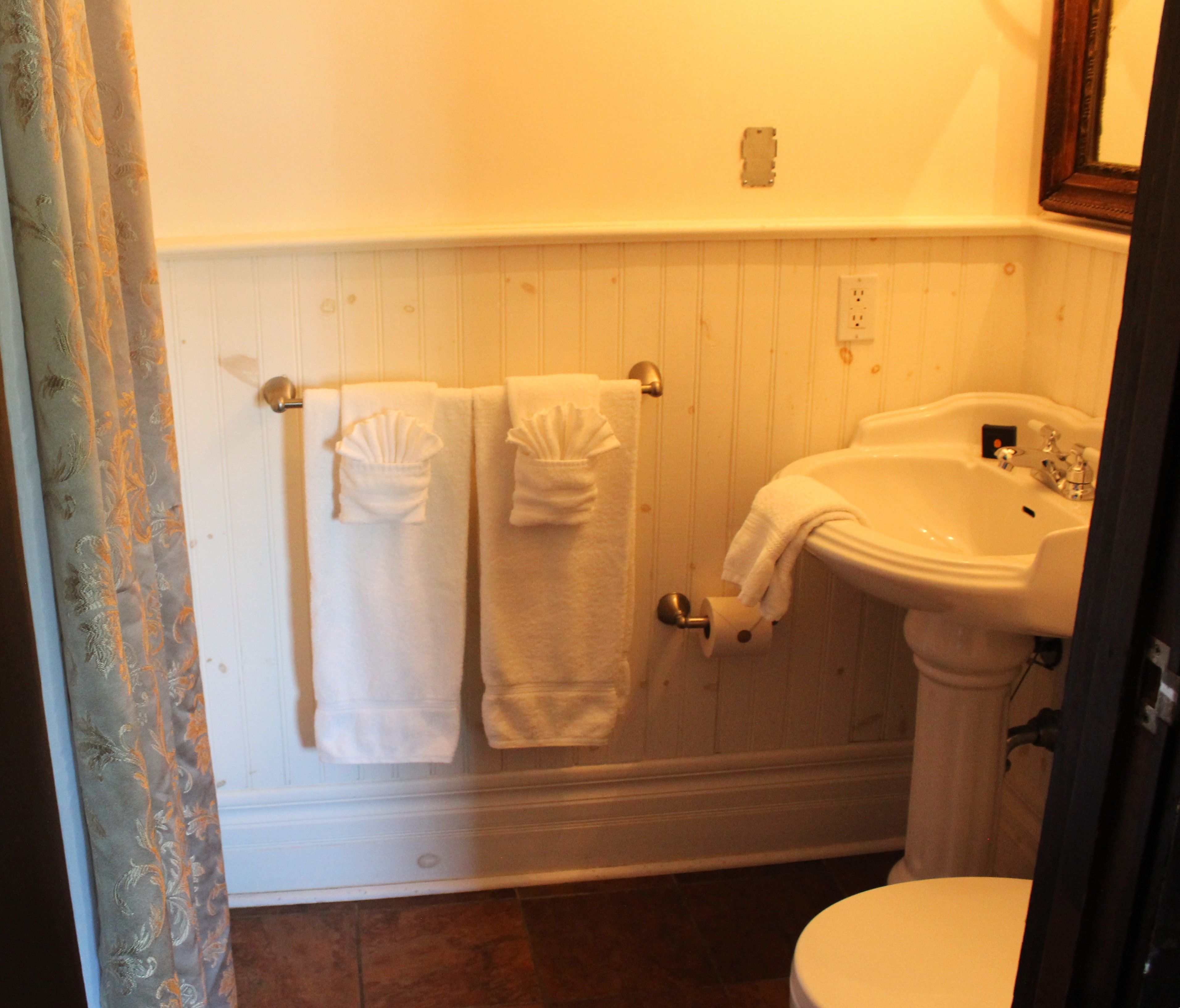 Een badkamer met toilet, wastafel en twee handdoekrekken met handdoeken.