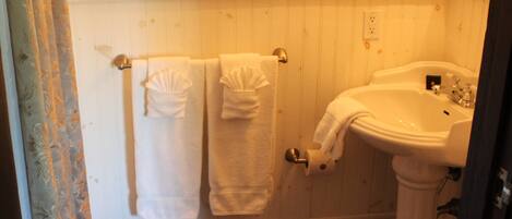 Een badkamer met toilet, wastafel en twee handdoekrekken met handdoeken.