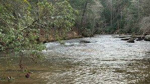 A river with rocks and a wooden bench in the foreground.