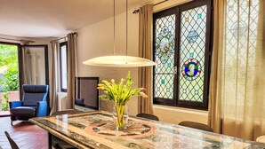 A dining area with a marble table, chairs, a vase with flowers, a hanging light, and a stained glass window. - Fiorita by Interhome (Brusino Arsizio)