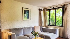 A living room with a grey sofa, a wooden coffee table with a red and white object, and a window with curtains. - Fiorita by Interhome (Brusino Arsizio)