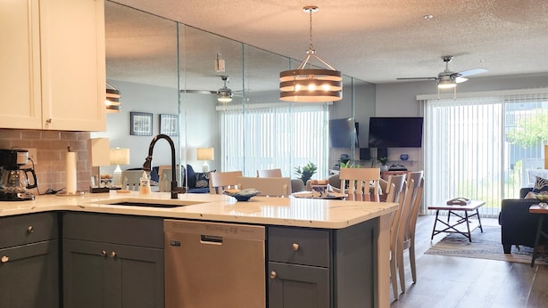Una cocina moderna con una isla central, armarios oscuros y lavavajillas.