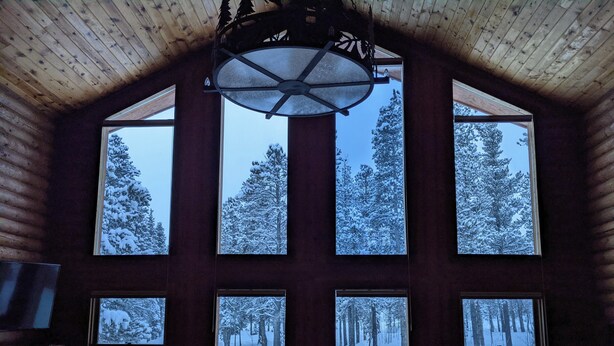 Een gezellig cabin interieur met grote ramen met uitzicht op een besneeuwd bos.