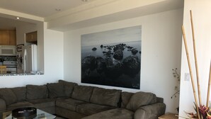 A modern living room with a grey sectional sofa, a glass coffee table, and a large abstract painting on the wall. - K38 Club Marena Ground Floor With Big Patio Walkout to Fantastic Surfing (Rosarito)