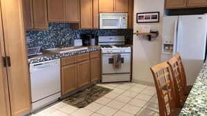 A kitchen with wooden cabinets, a microwave, an oven, a dishwasher, and a tiled backsplash. - K38 Club Marena Ground Floor With Big Patio Walkout to Fantastic Surfing (Rosarito)