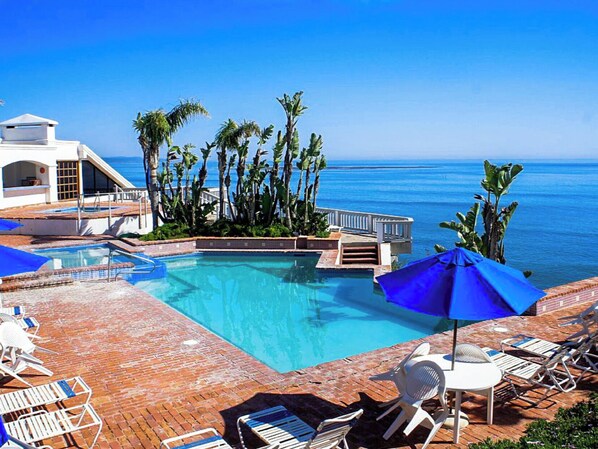 Relax by the oceanfront pool surrounded by palm trees and lounge chairs.