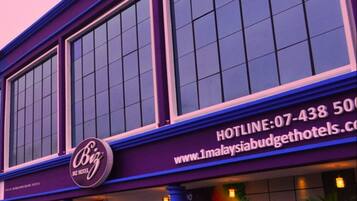 A building with large windows and a sign for 'Biz Hotel'.