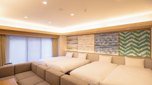 A hotel room with two beds, a sofa, and a wooden table. - GOLDSTAY SAKAE (Nagoya)